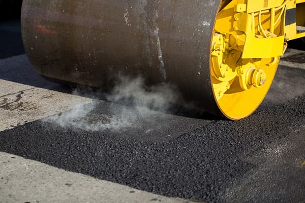 Roller compacting a hot mix asphalt patch on a commercial lot